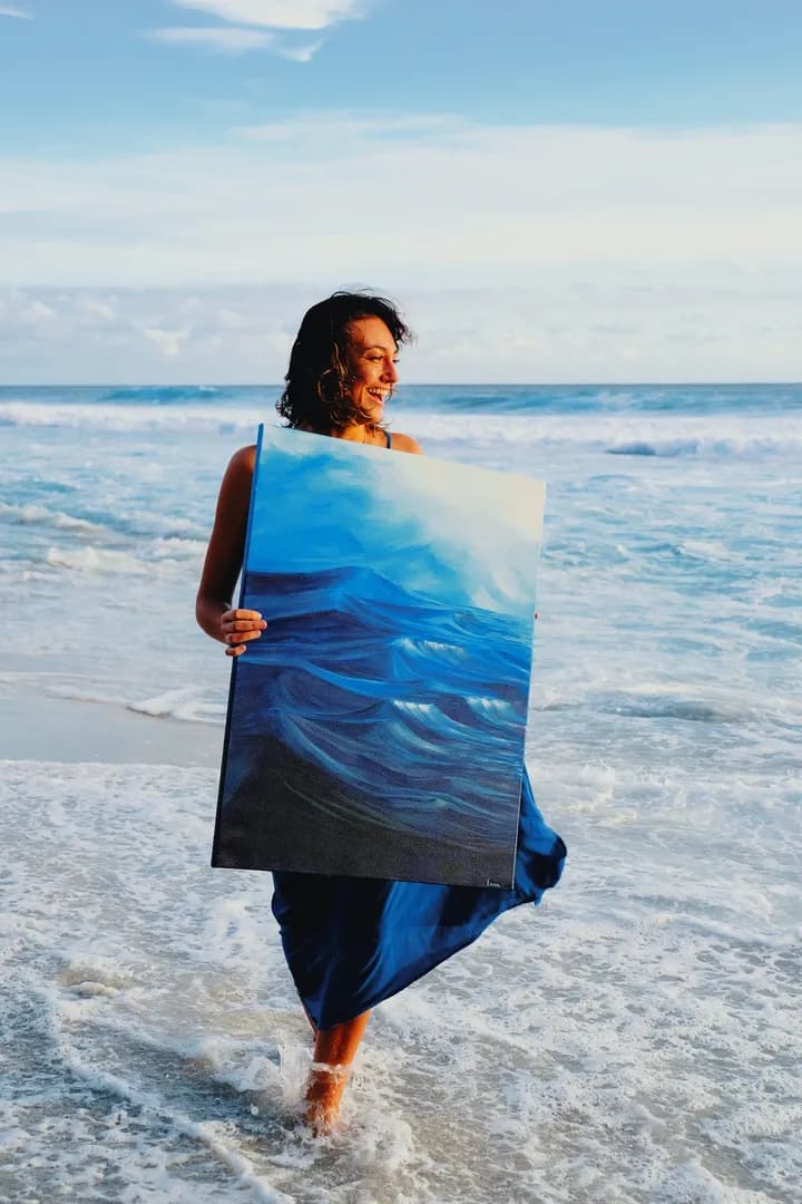 Lucie Caruso — Lusea, artiste peintre, sur une plage de La Réunion avec une de ses œuvres océaniques